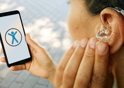 Image of a hearing impaired woman with a phone displaying the accessibility icon