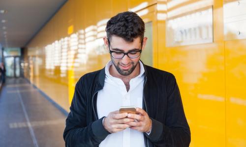 Caucasian man in a public space on his smart phone